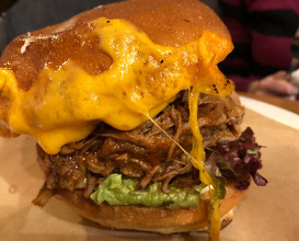 Brioche bun with pulled pork, lettuce, tomato, cheddar, caramelised red onion and homemade pickles